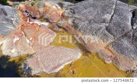 Abstract Rock Textures and Shallow Reddish Water in a Stream Bed Abstract Rock Textures and Shallow Reddish Water in a Stream Bed 127548672