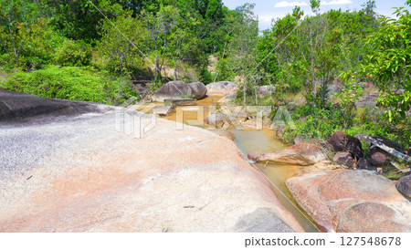 Tropical Stream Flowing Through Eroded Rock Formations in Rainforest Landscape 127548678
