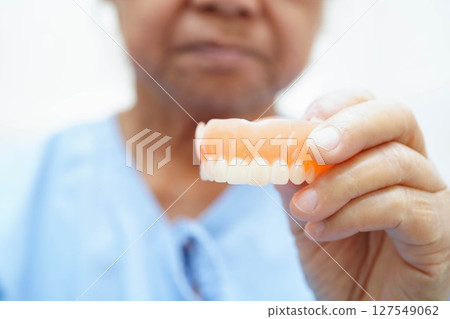 Asian senior woman patient holding teeth denture in her hand for chew food. 127549062
