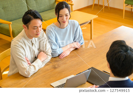 A Japanese couple receiving explanations from a man in a suit in the living room A Japanese couple receiving explanations from a man in a suit in the living room 127549915