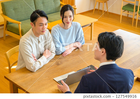 A Japanese couple receiving explanations from a man in a suit in the living room 127549916