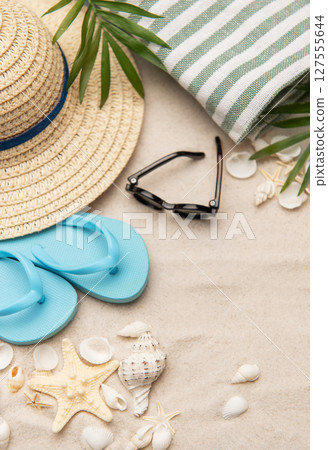 Beach accessories lying on sand creating summer vacation background Beach accessories lying on sand creating summer vacation background 127555644