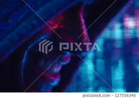 Smirking hoodlum hacker con man in neon lights: bad guy cyberpunk hacking portrait 127556340