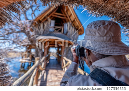In the Kruger National Park, a famous travel destination in South Africa, a tourist is utilizing binoculars from a viewpoint to observe the scenic and colorful landscape with wildlife, overlooking 127556833