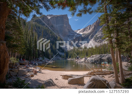 A woman hiking sits on the shores of Dream Lake, with Hallett peak visible in the distance, located in Rocky Mountain National Park, Estes Park, Colorado, United States 127557293