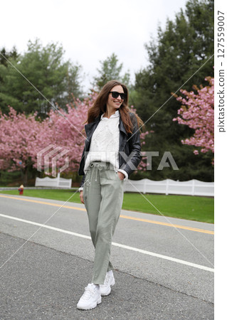 Young smiling brunette woman against a background of blooming trees Young smiling brunette woman against a background of blooming trees 127559007