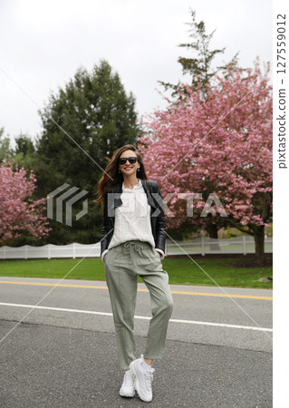 Young smiling brunette woman against a background of blooming trees 127559012