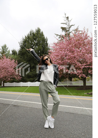 Young smiling brunette woman against a background of blooming trees 127559013
