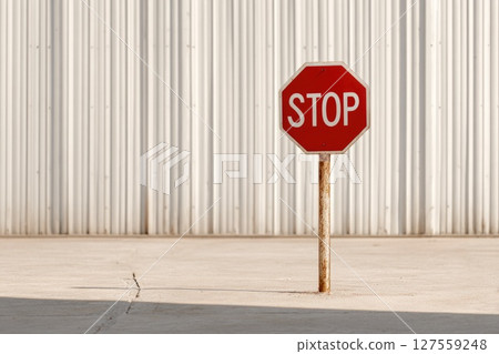 Old Rusty Stop Sign in Industrial Setting 127559248