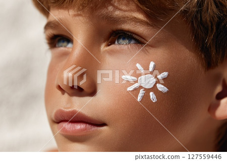 Boy with Sunblock Painted Like Sun on Cheek Looking Up Boy with Sunblock Painted Like Sun on Cheek Looking Up 127559446