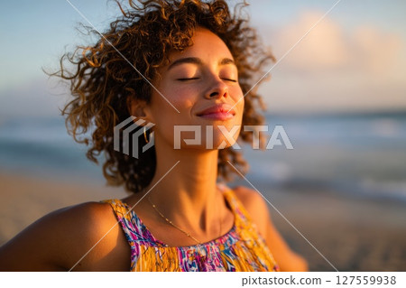 Peaceful Woman Embracing Sunset on the Beach 127559938