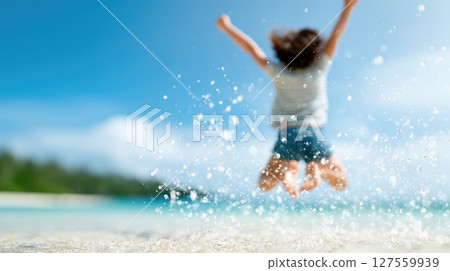 Child Jumping Joyfully on the Beach with Splash 127559939