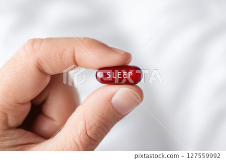 Red Sleep Pill Held Between Fingers Red Sleep Pill Held Between Fingers 127559992