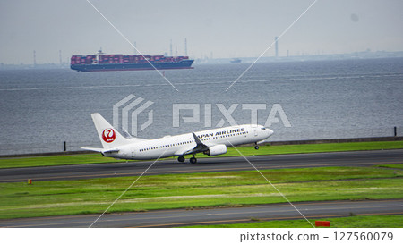 JAL plane taking off and container ship JAL plane taking off and container ship 127560079