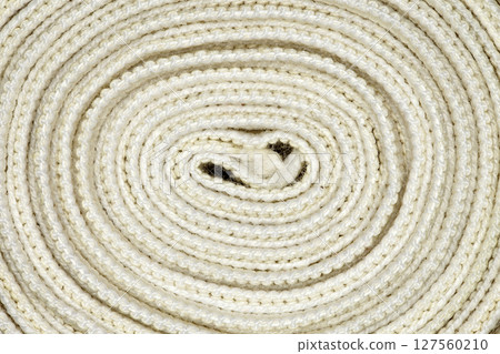 Elastic bandage twisted into coil in spiral close-up full depth of field Elastic bandage twisted into coil in spiral close-up full depth of field 127560210