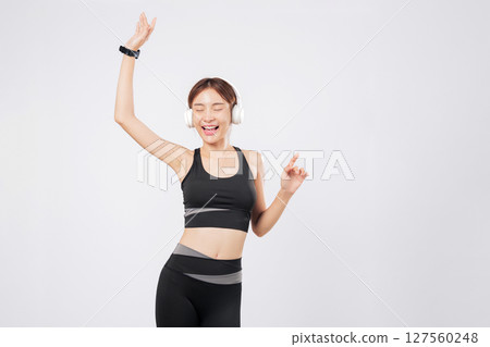 Dance is her mood today, with headphones on and music up loud. She spins, then pauses, and returns to dance with joy, embracing fitness and freedom. isolated studio white background Dance is her mood today, with headphones on and music up loud. She spins, then pauses, and returns to dance with joy, embracing fitness and freedom. isolated studio white background 127560248