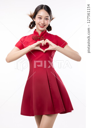 Portrait of joyful beauty Asian woman in red Cheongsam Chinese traditional dress celebrating and making heart shape hand sign isolated on white background. 127561154