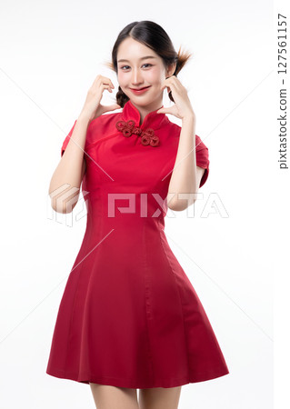 Portrait of joyful beauty Asian woman in red Cheongsam Chinese traditional dress celebrating and making heart shape hand sign isolated on white background. 127561157