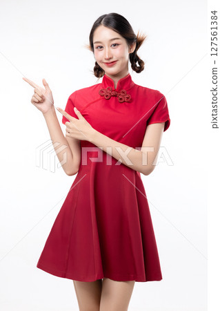 Portrait of joyful beauty Asian woman in red Cheongsam Chinese traditional dress celebrating and pointing finger to copy space isolated on white background. 127561384