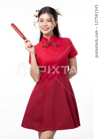 Portrait of joyful beauty Asian woman in red Cheongsam Chinese traditional dress pointing red fan for Chinese New Year festival content. 127561545