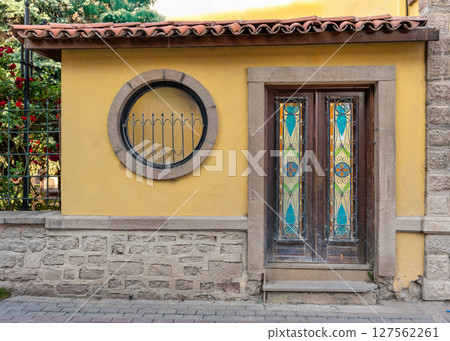 Facade of a traditional house with a stained glass door and round window in an old town 127562261