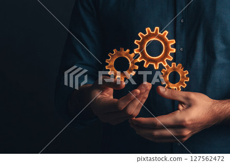 Hands holding glowing gears with economic symbols inside, representing policy mechanisms in action, economic reform, policy mechanics Hands holding glowing gears with economic symbols inside, representing policy mechanisms in action, economic reform, policy mechanics 127562472