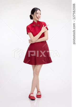 Full body portrait of joyful beauty Asian woman in red Cheongsam Chinese traditional dress celebrating and pointing finger to copy space isolated on white background. Full body portrait of joyful beauty Asian woman in red Cheongsam Chinese traditional dress celebrating and pointing finger to copy space isolated on white background. 127562886