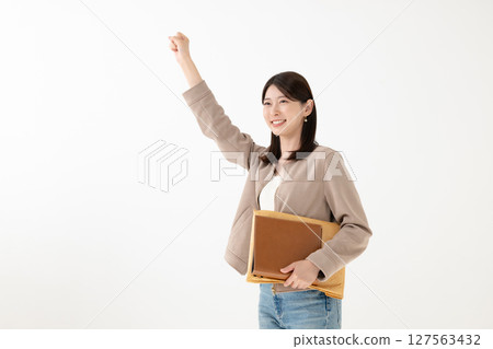 A young woman doing a fist pump while holding a computer A young woman doing a fist pump while holding a computer 127563432