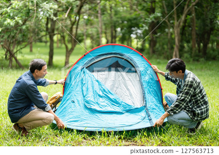 Family teamwork in camping. Father and son setting up a tent together. Family teamwork in camping. Father and son setting up a tent together. 127563713