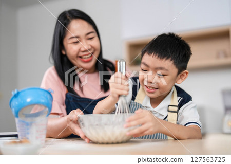 Family cooking together. A mother and son happily preparing a meal in the kitchen. Family cooking together. A mother and son happily preparing a meal in the kitchen. 127563725
