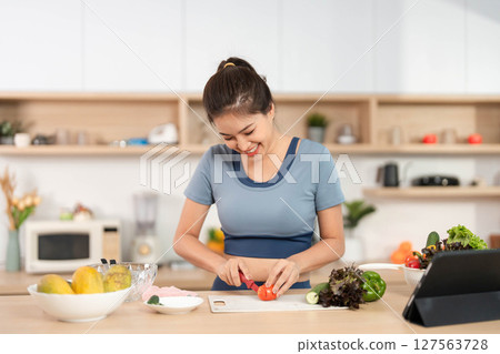 ESG and Healthy Living. Woman preparing fresh vegetables in a modern kitchen. 127563728