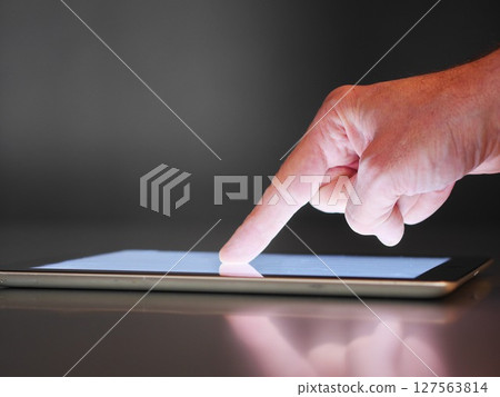 A hand pointing at a tablet screen 127563814