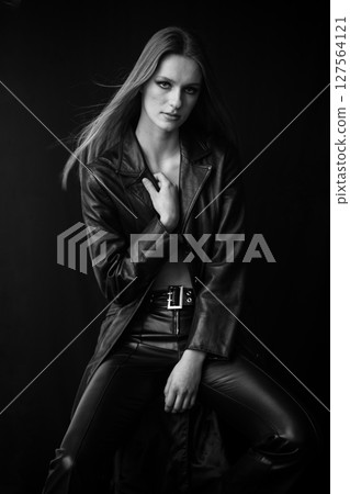 Timeless intensity - black and white portrait of a woman in leather, seated with a strong pose, her intense gaze radiating power and confidence, contrasted against a dark backdrop for a cinematic edge Timeless intensity - black and white portrait of a woman in leather, seated with a strong pose, her intense gaze radiating power and confidence, contrasted against a dark backdrop for a cinematic edge 127564121