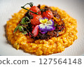 Creamy saffron risotto topped with braised beef, roasted cherry tomatoes, and edible flowers. Delicious gourmet Italian cuisine served in a modern restaurant setting 127564148