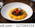Rich saffron risotto with tender braised beef, roasted cherry tomatoes, and vibrant edible flowers. Exquisite Italian dish presented beautifully for a fine dining experience 127564154