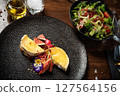 Cheese plate with figs and edible flowers. Fresh salad with tomatoes and greens. Fine dining presentation in a modern restaurant. Healthy and delicious gourmet meal closeup 127564156