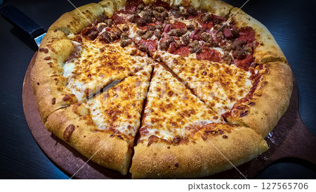 Delicious pizza featuring a combination of cheese and meat lovers toppings, served on a wooden board. The golden cheese stuffed crust Delicious pizza featuring a combination of cheese and meat lovers toppings, served on a wooden board. The golden cheese stuffed crust 127565706