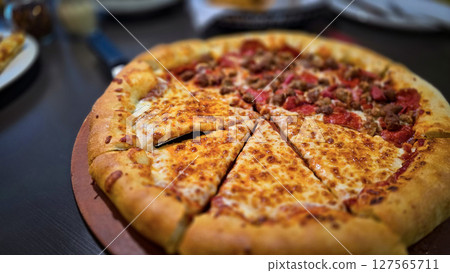 Delicious pizza featuring a combination of cheese and meat lovers toppings, served on a wooden board. The golden cheese stuffed crust 127565711