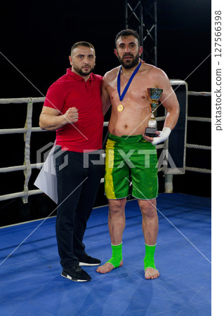 A boxer celebrates victory with his team in an emotional embrace after a grueling match. 127566398