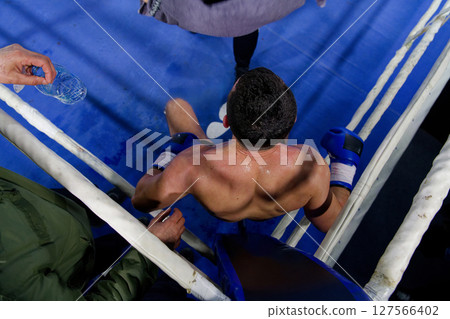 Top view of cornered boxer receives strategic advice from trainer during intense bout. 127566402