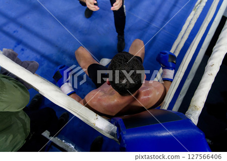 Top view of cornered boxer receives strategic advice from trainer during intense bout. Top view of cornered boxer receives strategic advice from trainer during intense bout. 127566406