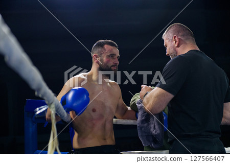 Cornered boxer receives strategic advice from trainer during intense bout. 127566407