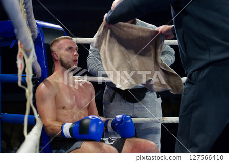 Cornered boxer receives strategic advice from trainer during intense bout. 127566410