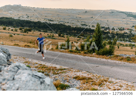 Empowered Runner Embracing Nature's Beauty on a Serene Morning Trail. 127566506