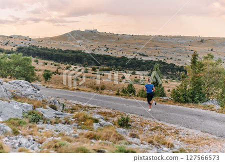 Empowered Runner Embracing Nature's Beauty on a Serene Morning Trail. 127566573
