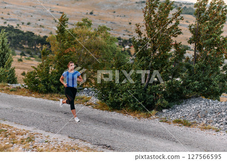 Empowered Runner Embracing Nature's Beauty on a Serene Morning Trail. 127566595