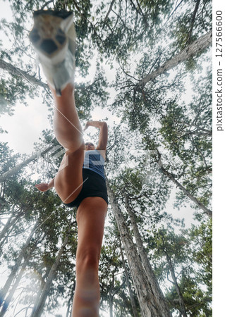 Adventurous Woman Overcoming Forest Obstacles with Determination and Agility. Adventurous Woman Overcoming Forest Obstacles with Determination and Agility. 127566600
