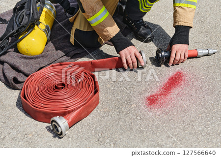 Professional Firefighter Cleaning Up Fire Hose After Extinguishing Blaze Professional Firefighter Cleaning Up Fire Hose After Extinguishing Blaze 127566640