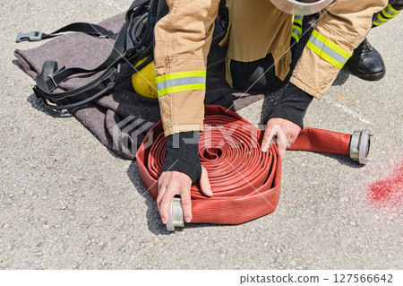 Professional Firefighter Cleaning Up Fire Hose After Extinguishing Blaze 127566642