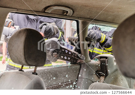 A dedicated team of professional firefighters employs specialized tools to cut and break through vehicle wreckage, showcasing their skilled collaboration and swift response in rescuing individuals 127566644